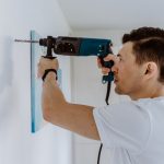 Husband for hour home repairing service. Portrait of handyman drilling a hole in wall